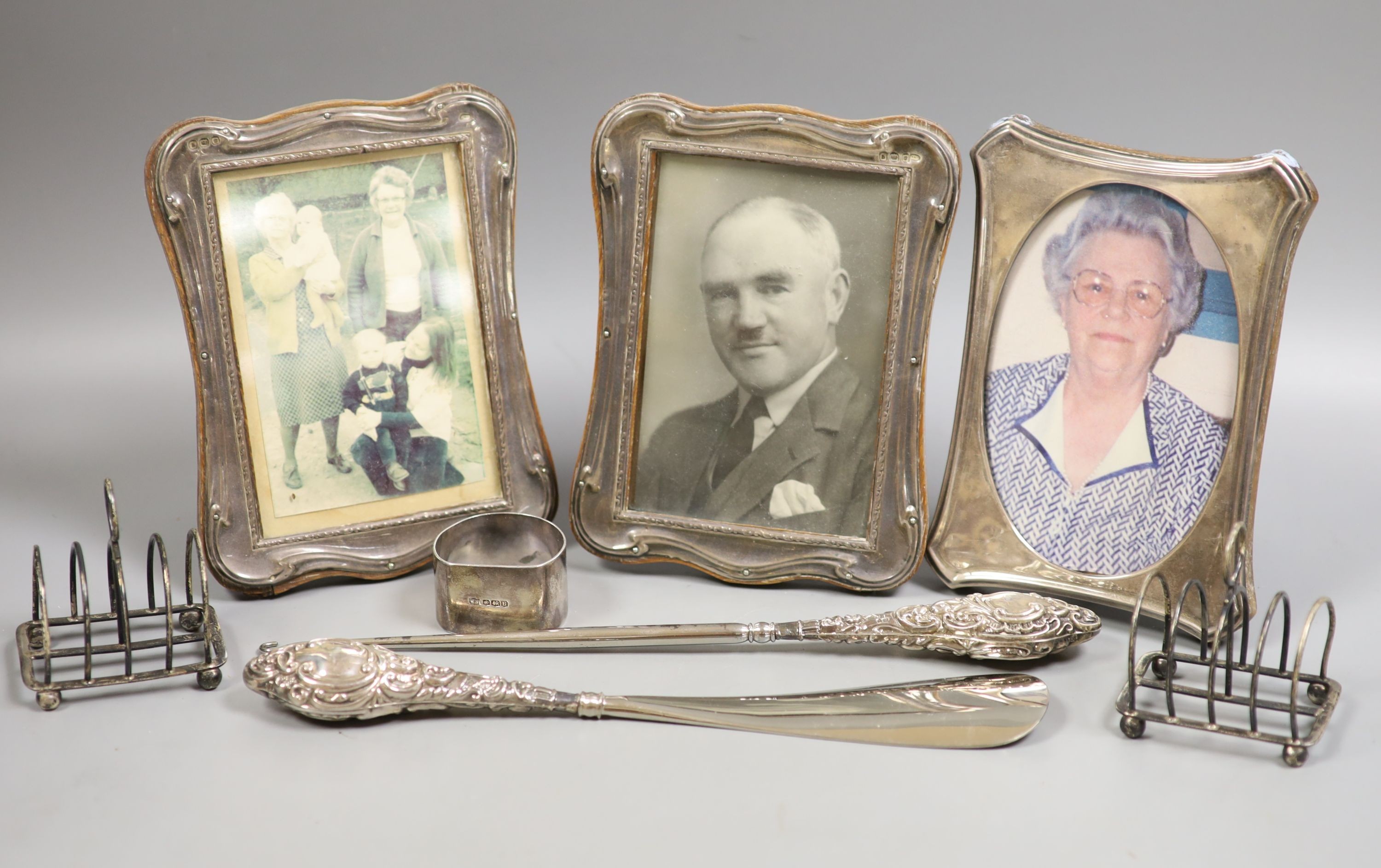 A pair of George V silver mounted photograph frames, Birmingham, 1915, 17.2cm, one other frame, a pair of small silver toast racks, a silver napkin ring, a silver mounted button hook and shoehorn.